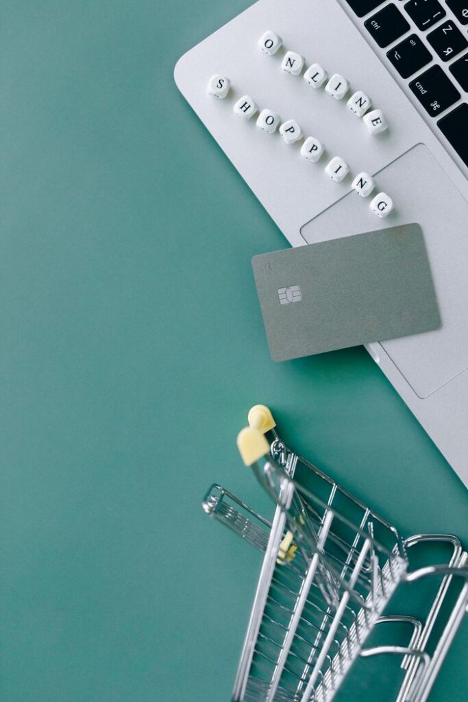 Image showcasing online shopping with a laptop, bank card, and mini cart.